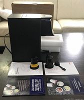 Coffee maker with accessories and paperwork on table