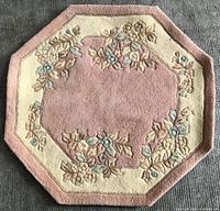 Full view of octagonal pink and cream wool rug with floral design