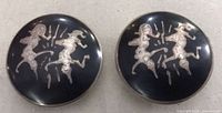 Front view showing round sterling silver clip-on earrings with black enamel and etched figures