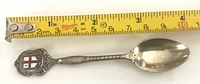 Full view of sterling silver spoon beside tape measure showing length