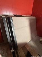 Stacked beige fabric room divider panels with metal frames leaning against wall