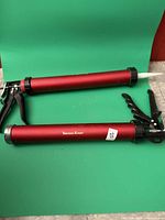 Both caulking guns full view on green background