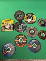 Group view of boxed RTRMAX saw blade and approx. 11 abrasive discs