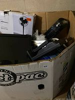 Overview of skid showing tower fan, boxed stand fan and mixed items