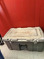 Closed gray plastic toolbox against red wall