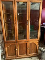 Full view of wooden china cabinet with three glass doors, lower wooden doors