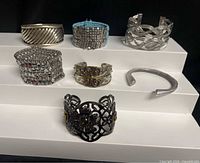 Group shot of seven mixed-metal cuff bracelets on tiered display