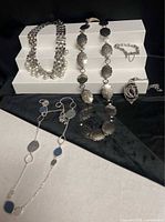 Group shot of all five jewelry items displayed on white risers and black cloth