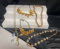 All five necklaces displayed on tiered white risers