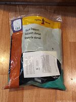 Front of plastic bag showing belt inside and printed multilingual back support text