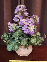 Front view of purple silk flower arrangement in white ceramic pot showing full shape and color