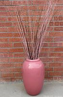 Full view of pink ceramic floor vase with branches displaying scale and color