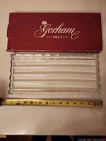 Full view of dish beside tape showing length and included box