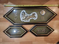 Three framed plaques with measuring tape showing largest length