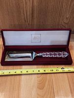Cake server in presentation box with measuring tape showing length