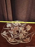 Top view of entire clear glass bowl showing floral design and scalloped rim with measuring tape indicating size