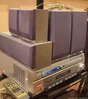 Front view of receiver/amplifier with satellites stacked on top, remote and speaker wire visible