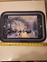 Full view of rectangular metal tray with winter scene and ruler for scale