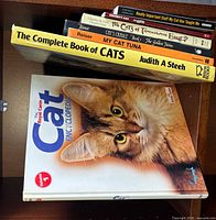 Stacked view of several titles on shelf plus Cat Encyclopedia and Complete Book of Cats