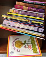 Side view of stacked books revealing spines including Hyena Family, Ever After High: The Storybook of Legends, Storybook Collection and others