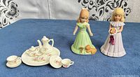 Full lot: two figurines and complete tea set on blue surface