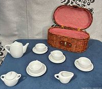 Complete miniature porcelain tea set displayed with wicker basket