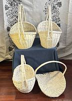 Four white wicker baskets displayed together