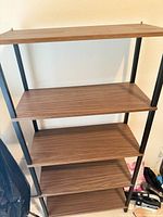 Front view showing all five brown wood grain shelves and black metal frame