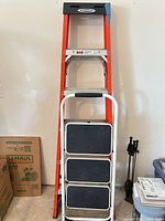 Werner A-frame ladder standing against wall with folding 3-step stool nested in front