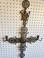 Front view of brass cross showing rosette panels, archangel, candle sconces, hooks