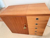 Closed teak veneer sewing cabinet with left door and right drawer stack, key visible