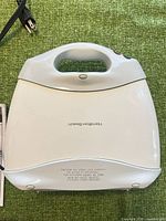 Top view of waffle maker showing white housing, handle, power cord