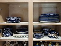 Cabinet view of all Bolesławiec style pieces: bowls, plates, mugs, baker