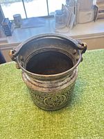 Top view of engraved vessel showing swing handle and decorative body