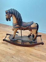 Full left-side view of wooden rocking horse on curved base with wheels