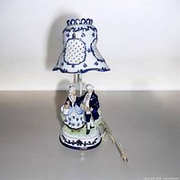 Full view of porcelain figurine lamp with shade and cord