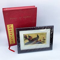 Framed artwork leaning against closed red presentation box