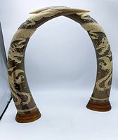 Full view of two carved horns on wooden bases crossing at top