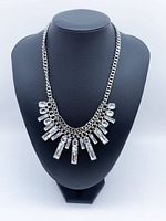 Front view of silver-tone bib necklace on display bust showing crystal fringe design