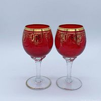 Front view of both ruby red crystal wine glasses showing gold gilt and twisted stems