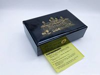 Closed black lacquer jewelry box with gold motif and instruction sheet