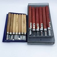 Two boxed sets of Japanese chisels, natural and red handles visible