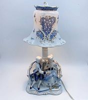 Full view of porcelain lamp off showing figurine base and pierced shade