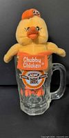 Chubby Chicken plush seated inside glass mug, front logo visible