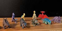Front view of all nine dinosaur figurines lined in a row on wood surface
