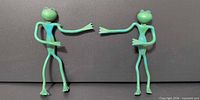Two green plastic frog figurines standing apart, front view