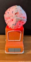 Front view of orange plastic ice cream truck with plush light-up scoop
