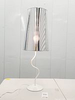 Full lamp lit showing chrome shade reflection and squiggle stem