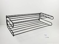 Front angled view of black wire wall rack showing two tiers and side profile