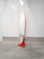 Front view of tall red floor mirror showing full oval mirror and pedestal base